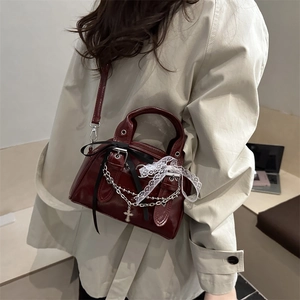 Deep red baguette bag with bows and silver cross chain worn over a beige trench coat