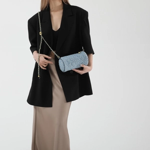 Sac cylindrique matelassé bleu denim porté par un mannequin en tenue minimaliste