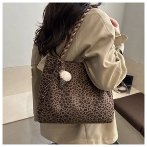 Dettaglio della borsa tote leopardata con manici intrecciati e ciondolo di peluche