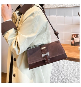 Detail of dark brown suede and leather shoulder bag with a silver metal buckle
