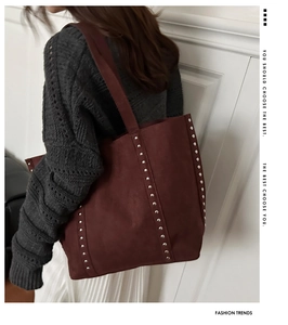 Macro detail of wine red suede tote bag featuring silver rivet studs on the side panel