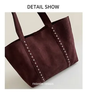 Close-up of deep wine red suede tote bag featuring vertical silver rivet detail and double straps
