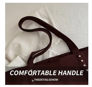 Detailed close-up of dark brown tote bag with silver rivets and sturdy wide handles