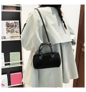 Détail du sac boston noir en peluche avec poignées en cuir et bandoulière