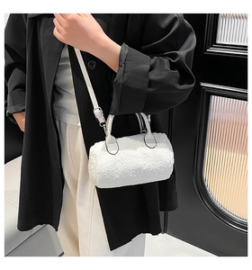 Detail of white faux shearling boston bag showing plush texture and leather strap