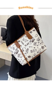 Detail of graffiti tote bag with brown leather handles and comic print patterns