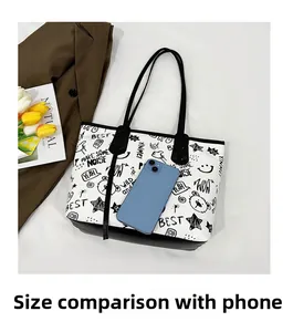 Detail view of large white graffiti tote bag with bear print showing size scale against a phone