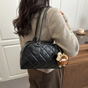 Quilted black tote bag with plush charm, perfect for casual winter fashion styling