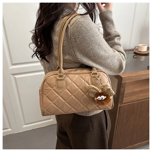 Close-up of khaki quilted tote bag featuring a cute plush insect charm in home setting