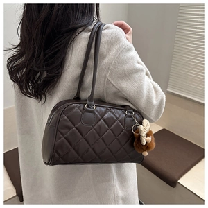 Close-up of brown quilted tote bag with diamond pattern and plush bear charm