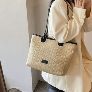 Minimalist woven straw tote bag with black leather handles for summer beach vacations