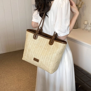 Straw woven tote bag with brown leather handles and trim for summer beach vacation