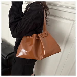 Detail of caramel tote bag in shiny synthetic leather with stylish pleated texture