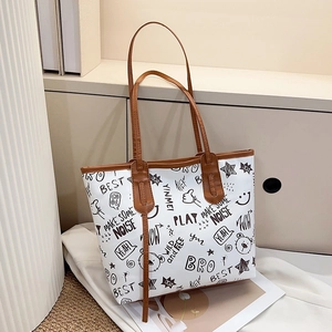 Close-up of graffiti print tote bag with brown leather handles and cartoon patterns