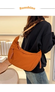 Detail showing orange nylon dumpling bag with adjustable strap and zip rope puller