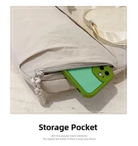 Detail of a beige nylon crossbody bag front storage pocket holding a smartphone