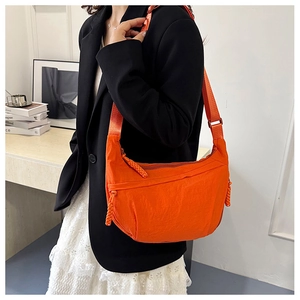 Modella che indossa una borsa a mezzaluna arancione in nylon con zip intrecciata