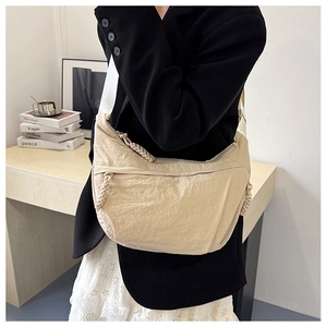 Detail of light beige nylon crescent bag with braided knot zipper and canvas strap