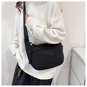 Detail of black nylon crescent bag featuring a textured woven knot zipper pull and strap