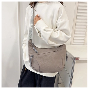 Detail of grey nylon crescent bag with silver strap and braided rope zipper pull