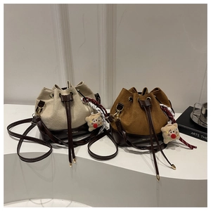 Detail of drawstring bucket bags in beige and caramel with contrast stitching and star charm