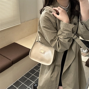 Chic beige PU leather hobo shoulder bag with gold logo plate on a stylish model