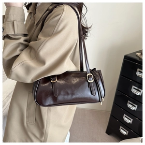 Detail of glossy brown underarm bag showing gold hardware and double shoulder straps