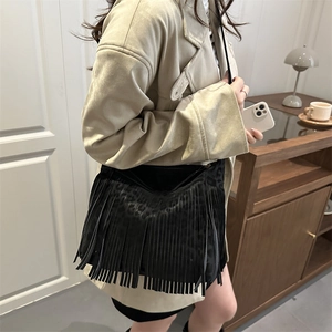 Minimalist black fringe tote bag with leopard print texture worn by model in a cozy room
