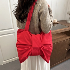 Chic oversized red bow tote bag shown from a back perspective on model