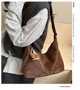 Brown moon-shaped hobo bag with a cute bear pendant worn by a model in casual style