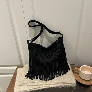 Detail of bohemian black suede hobo bag featuring long tassels and adjustable shoulder strap