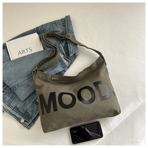 Flat lay of army green canvas hobo bag with MOOD lettering and casual accessories