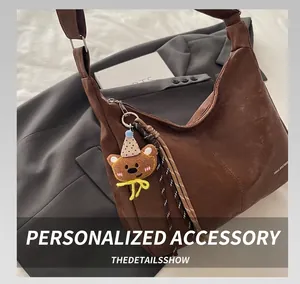 Detailed close-up of brown suede crescent bag with cute bear charm and woven drawstring