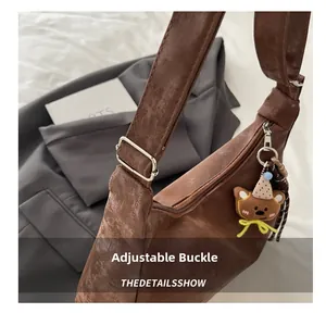 Detail of adjustable silver buckle and cute plush bear charm on a brown suede handbag