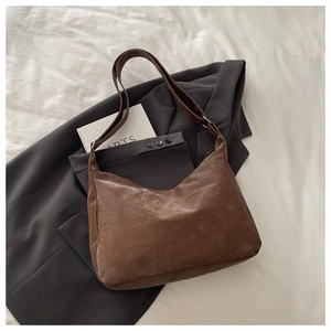 Detailed flat lay of brown suede hobo bag with adjustable strap and metal hardware