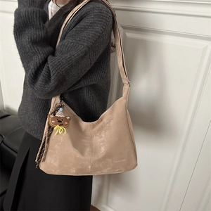 Sand leather tote bag with adjustable strap and cute bear charm shown on model