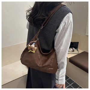 Detail of vintage brown tote bag with plush bear charm and soft wrinkled leather texture