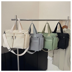 Detail view of large canvas tote bags in four colors with multiple zipper pockets