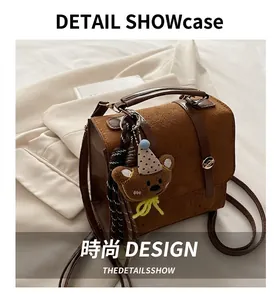 Detailed view of a brown vintage satchel with suede stitching and a cute teddy bear charm
