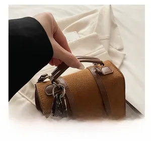 Detail of vintage brown suede handbag with leather handles and cute bear charm accessory