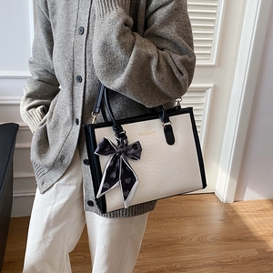 Large color-block tote bag with snake skin texture and decorative silk scarf shown on model