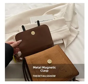 Detail of magnetic metal snap closure and textured matte leather on brown shoulder bag