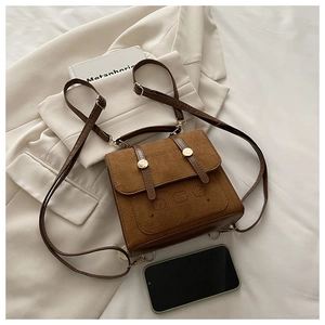 Detail of retro brown suede backpack with bear embossing and leather trim near a smartphone