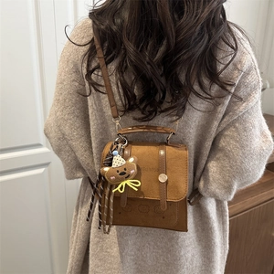 Brown suede crossbody bag with bear pendant and embossed patterns for stylish women