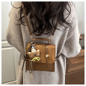 Detail of a brown velvet mini backpack featuring a bear pattern and cute plush bear charm