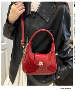 Detail of red patent leather crescent bag with golden metal twist lock and smooth texture