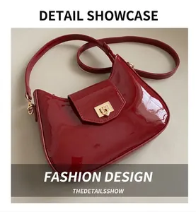 Close-up of wine red patent leather shoulder bag with glossy finish and gold buckle