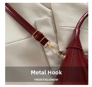Detail of premium gold metal hook and buckle on burgundy patent leather handbag