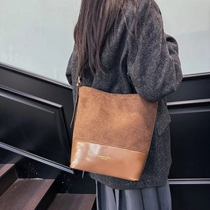 Sac seau marron minimaliste en daim et cuir lisse porté par un mannequin femme