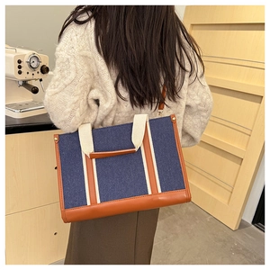 Lifestyle shot showing the back of a large capacity navy denim tote bag with leather trim